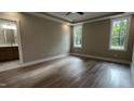 Bright main bedroom with hardwood floors, tray ceilings, two large windows, and an en-suite bathroom at 2405 Pearces Rd, Zebulon, NC 27597