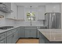 Well-appointed kitchen with modern stainless steel appliances, gray lower cabinets, and light hardwood floors at 2505 Catalina Ct, Raleigh, NC 27607