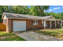 Brick home with attached garage, manicured lawn, and a covered porch with a charming porch swing at 2614 Cambridge Rd, Burlington, NC 27215