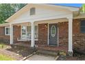 Charming front porch with brick columns, a porch swing, and decorative front door at 2614 Cambridge Rd, Burlington, NC 27215