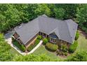 Aerial view of a brick home with a dark roof surrounded by mature trees in a wooded neighborhood at 27 Woodgate Ct, Durham, NC 27713