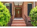 Elegant front door with decorative glass and brick steps framed by manicured greenery and black shutters at 27 Woodgate Ct, Durham, NC 27713