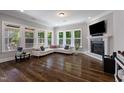 Spacious living room featuring hardwood floors, a fireplace, and large windows overlooking the backyard at 3029 Mountain Hill Dr, Wake Forest, NC 27587