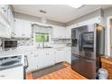 Bright kitchen featuring stainless steel appliances, white cabinets, tile backsplash, and wood flooring at 304 Cornelia Dr, Graham, NC 27253