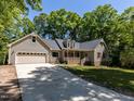 Inviting front exterior featuring a long driveway and a charming covered porch, surrounded by mature trees at 312 Heidinger Dr, Cary, NC 27511