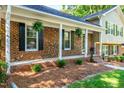 Inviting front porch with brick facade, stylish columns, and hanging plants for an outdoor feel at 3301 Manor Ridge Dr, Raleigh, NC 27603