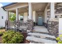 Inviting front porch with stone pillars, a blue front door, and stone steps at 521 Marion Hills Way, Knightdale, NC 27545