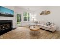 Cozy living room boasts a fireplace, white sectional, and lots of natural light at 7611 Satinwing Ln, Raleigh, NC 27617