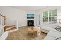 Bright living room features fireplace, white sectional, and wood-look floors at 7611 Satinwing Ln, Raleigh, NC 27617