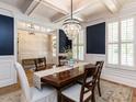 Elegant dining room with a crystal chandelier, wainscoting, and shuttered windows for natural light at 800 Skymont Dr, Holly Springs, NC 27540