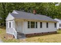 Quaint home with white siding, a covered porch, and a brick foundation nestled in a serene, tree-filled neighborhood at 1013 Graham St, Burlington, NC 27217