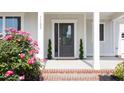 Close-up of front porch with gray door, decorative plants, and vibrant flowers at 1102 Birchbark Rd, Durham, NC 27705