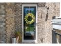 Close-up of a black front door with a decorative wreath and brick surround at 11549 Helmond Way # 107, Raleigh, NC 27617