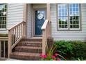 Inviting front door with decorative wreath, flanked by large windows and brick steps at 205 Windbyrne Dr, Cary, NC 27513