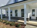 Close up of a charming front porch showcasing brick accents, white columns, and fresh landscaping at 2874 Quarry Rd # 165, Rolesville, NC 27571