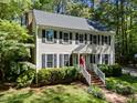 Charming two-story home featuring a gray roof, black shutters, and a lush, green, tree-filled yard at 404 Emerywood Dr, Raleigh, NC 27615