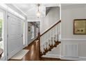 Bright foyer showcasing hardwood floors, a staircase with white railings, and a traditional chandelier at 404 Emerywood Dr, Raleigh, NC 27615