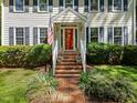 A red front door and brick steps lead to a well-maintained two-story home, framed by manicured landscaping at 404 Emerywood Dr, Raleigh, NC 27615