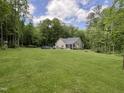 Spacious backyard featuring an above-ground pool, deck, lush grass, and mature trees, perfect for outdoor enjoyment at 4072 Mackenzie Dr, Haw River, NC 27258