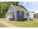 Inviting single-story home featuring blue siding, a classic white porch, and a beautifully maintained green lawn at 410 Caswell St, Burlington, NC 27217