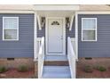 Close-up of the home's entrance, showcasing a white door, stylish lighting, and a well-maintained porch area at 410 Caswell St, Burlington, NC 27217
