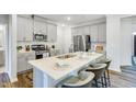 Modern kitchen with gray cabinets, stainless steel appliances, a large island with seating, and stylish pendant lighting at 740 Swim Cave Ln, Wendell, NC 27591