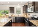 Stylish kitchen with dark cabinets, stainless steel appliances, granite countertops, and backyard access at 7508 Channery Way, Raleigh, NC 27616