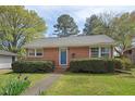 Charming brick home featuring a manicured lawn with lush shrubbery and a welcoming blue front door at 809 Leon St, Durham, NC 27704