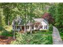 Aerial view showcasing a lovely white home, mature trees, a circular driveway, and manicured landscaping at 8304 Epping Forest Way, Wake Forest, NC 27587