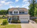 Two-story home with gray siding, black shutters, stone accents, green lawn and lush landscaping at 8616 Deep Elm Dr, Wake Forest, NC 27587