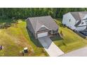 An aerial view of a well-manicured property with gray siding, brick accents, attached garage, and long driveway at 94 Shooting Star Ln, Clayton, NC 27520