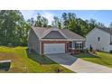 Well-kept one-story home with attached garage, gray siding, brick accents, and verdant lawn at 94 Shooting Star Ln, Clayton, NC 27520