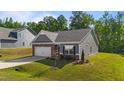 Cozy single-story house with a manicured lawn, attached garage, and complemented by lush, mature trees at 94 Shooting Star Ln, Clayton, NC 27520