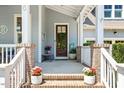 Inviting front porch with brick accents, potted plants, and a charming wooden front door at 120 Mearleaf Pl, Holly Springs, NC 27540