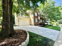 A two-story home with a wide driveway leading to a garage, framed by lush greenery and trees at 13017 Townfield Dr, Raleigh, NC 27614
