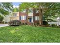 Traditional home with a well-kept lawn, featuring blue shutters, a brick facade, and a vibrant front door at 13017 Townfield Dr, Raleigh, NC 27614