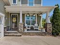 Inviting front porch with stone accents, comfortable seating and charming decorative details at 1701 Bodwin Ln, Apex, NC 27502