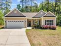 Charming single Gathering home with lush lawn and welcoming covered front entrance with stone accents and white garage door at 217 Griffis Dr, Stem, NC 27581
