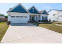 Charming single Gathering home showcasing blue and white color palette, a two car garage, and long concrete driveway at 218 E Tecoma Ln, Clayton, NC 27520