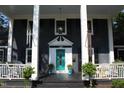 Inviting front porch with white columns and a vibrant turquoise front door at 300 S Pine St, Benson, NC 27504