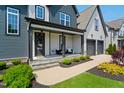 Inviting covered front porch with stylish seating, steps and a manicured lawn, welcoming guests to relax outdoors at 324 Prides Xing, Rolesville, NC 27571