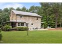Rustic log cabin showcasing a large backyard, stone chimney, metal roof, and a cozy patio area at 407 Howard Tant Rd, Zebulon, NC 27597