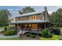 Charming log cabin with stone chimney and inviting wrap-around porch at 407 Howard Tant Rd, Zebulon, NC 27597