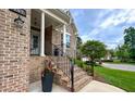 Inviting front porch with brick stairs, wrought iron railing, and a stylish flower pot on the steps at 409 Eagle Ct, Henderson, NC 27536