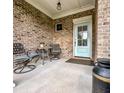 Cozy front porch with seating and a view of the front door, all brick, with a welcome mat at 409 Eagle Ct, Henderson, NC 27536