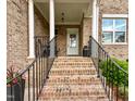 Elegant front porch with brick stairs, white columns, and a glimpse of the front door and well manicured landscape at 409 Eagle Ct, Henderson, NC 27536