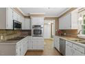 Traditional kitchen with white cabinets, stainless steel appliances, and warm-toned backsplash at 450 S Stratford Dr, Henderson, NC 27537