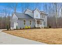 Charming two-story home featuring gray siding, black roof, and a cozy front porch with white railings and driveway at 596 Oaks Lane Rd, Timberlake, NC 27583