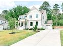 Stunning white two-story home with a manicured lawn and a long concrete driveway at 642 The Parks Dr, Pittsboro, NC 27312