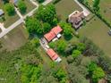 Aerial view of a sprawling property featuring a home and additional structure with a striking red roof surrounded by mature trees at 9108 Ransdell Rd, Raleigh, NC 27603